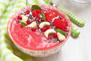 Raspberry pineapple banana smoothie bowl topping with berries and seeds