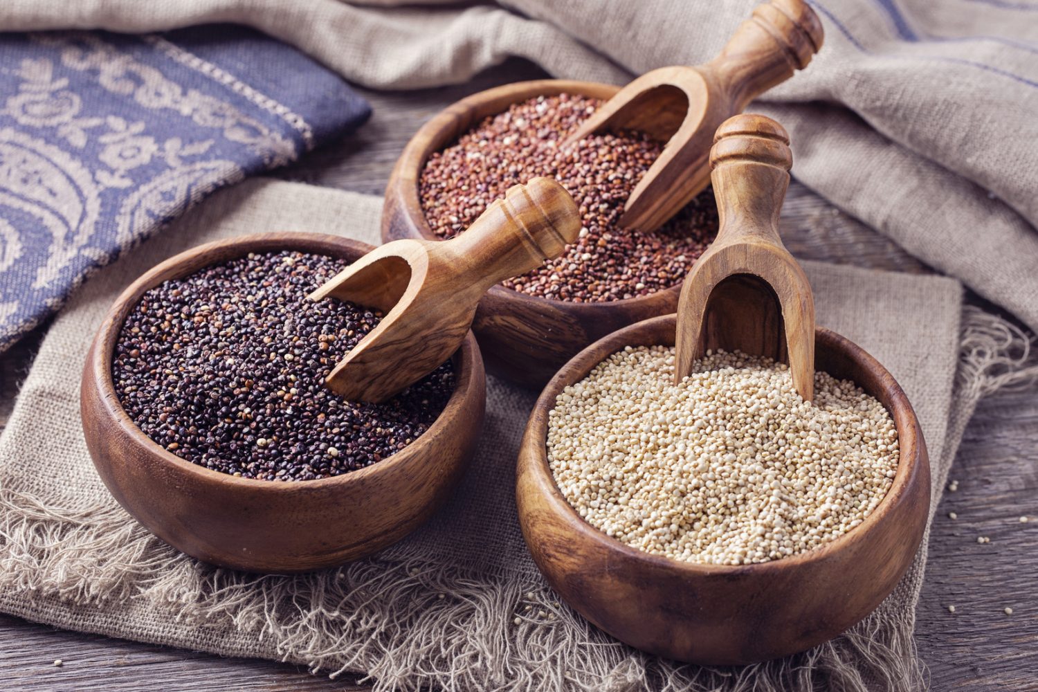 Red, black and white quinoa seeds on a wooden background